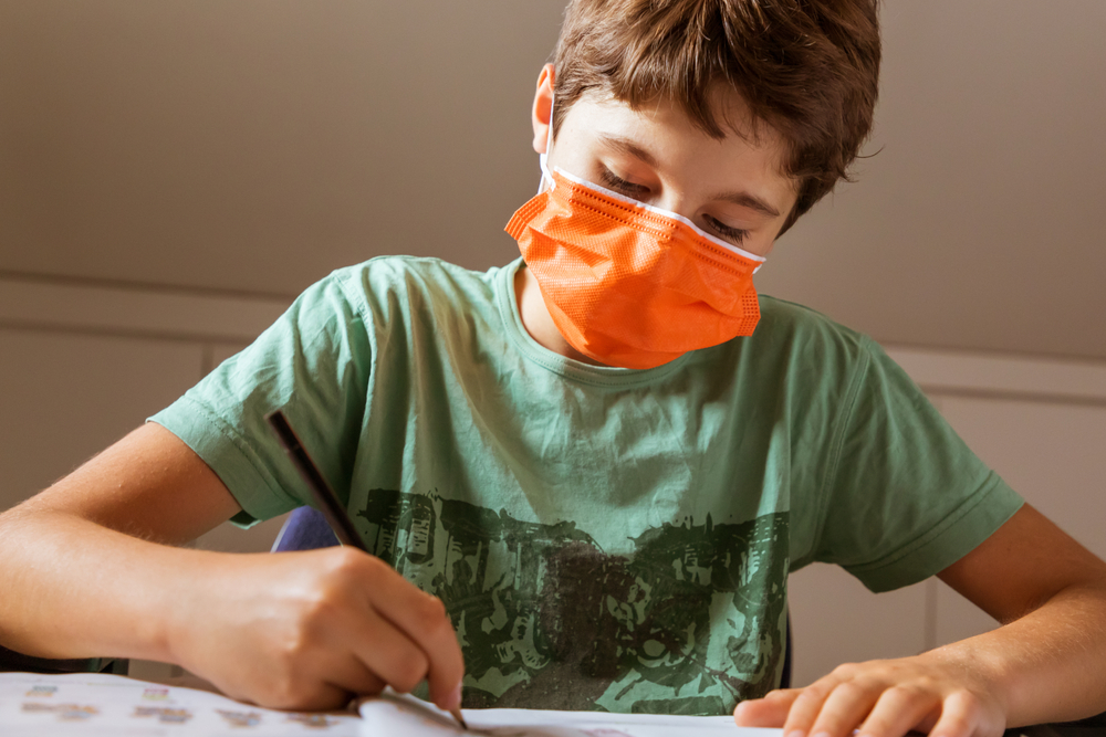 Boy in mask doing homework