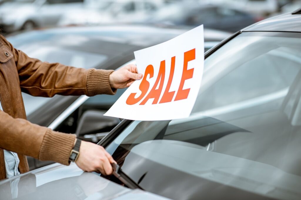 Person labeling a used car is now available for purchase