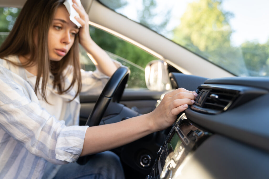 Girl checking her car's cooling system so she can stay cool while driving in hot weather